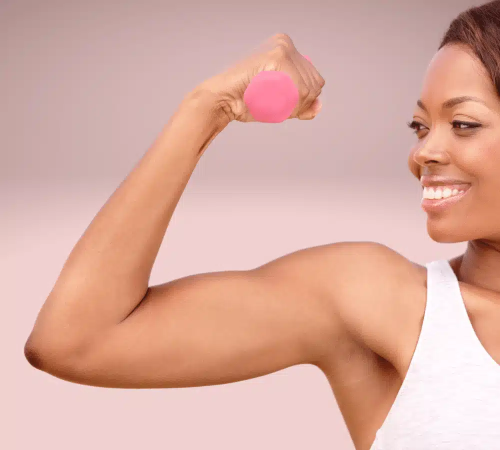 A woman is flexing her muscles with a pink dumbbell.
