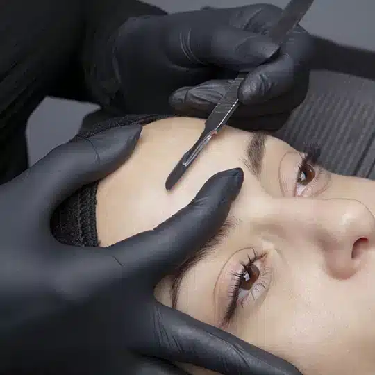 A woman getting her eyebrows waxed in a salon.