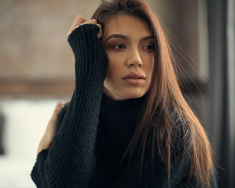 Woman with long brown hair, wearing a black turtle neck, looking to the side - Rhinoplasty in Grand Rapids